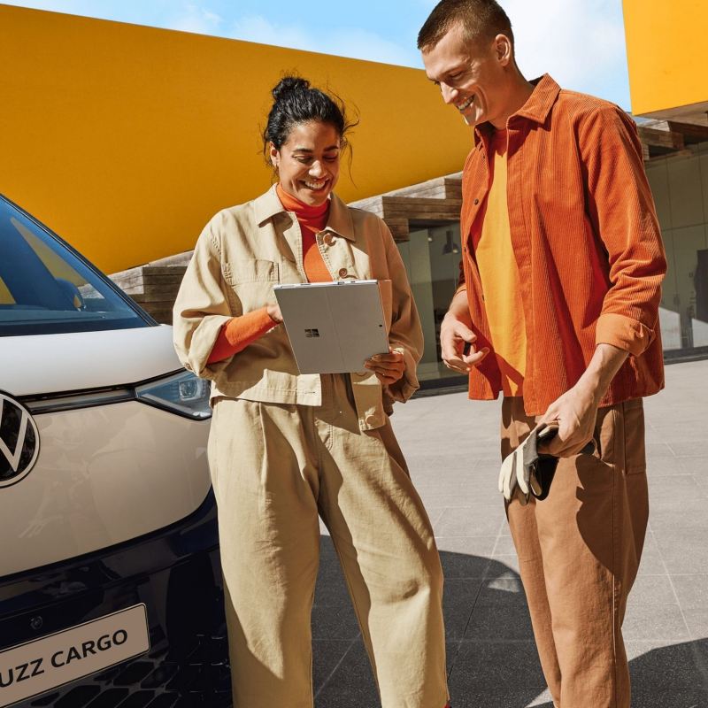 2 people stand in front of VW ID. Buzz Cargo with tablet