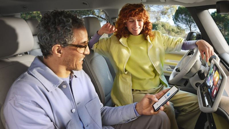 2 people on smartphone in a parked VW ID. Buzz