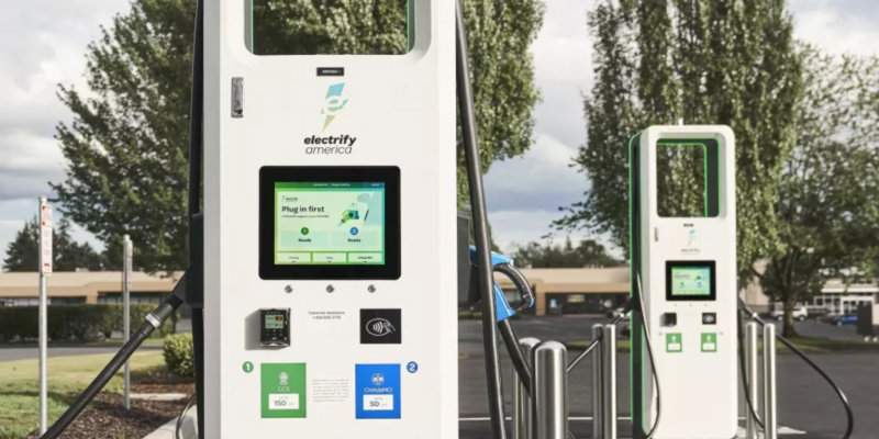 Electrify America charging stations for Volkswagen electric vehicles, featuring screens and payment options in a modern outdoor setting.