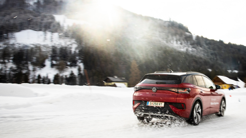 Der ID.4 GTX fährt von hinten durch den Schnee in Richtung Sonne