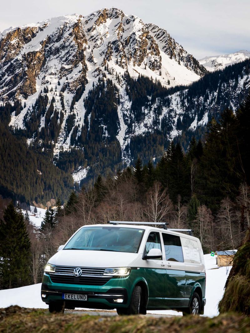 Vit och grön VW Transporter åker på landsväg i alperna