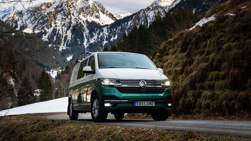 Vit och grön VW Transporter kör på landsväg i alperna