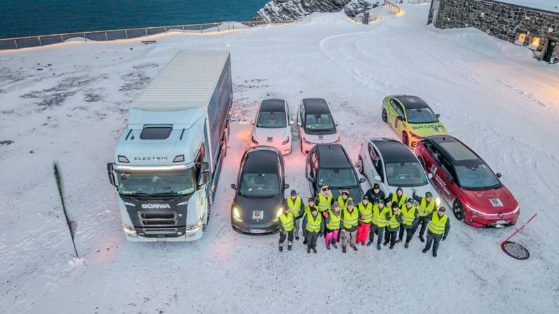 7 Elektroautos und ein Elektro LKW stehen auf einem schneebedeckten Platz