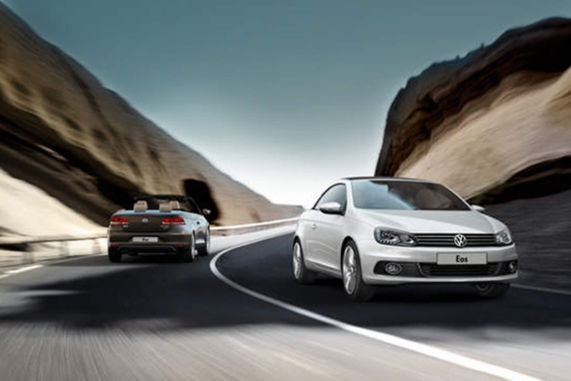 Two Volkswagen Eos' driving in opposite directions, through the mountains.