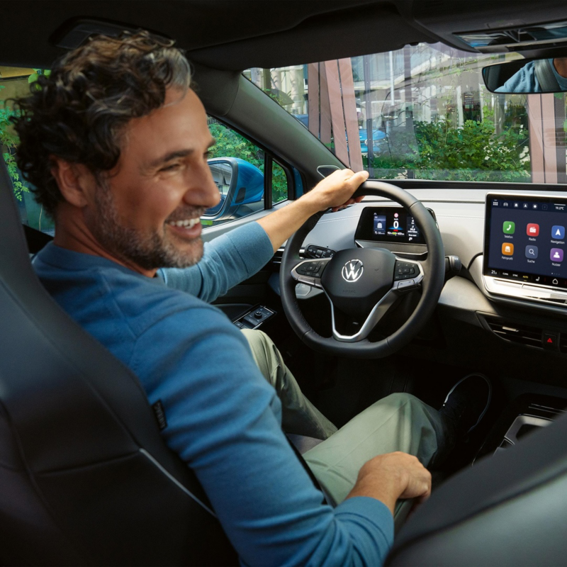 Un hombre sonriendo dentro de su Volkswagen sujetando el volante