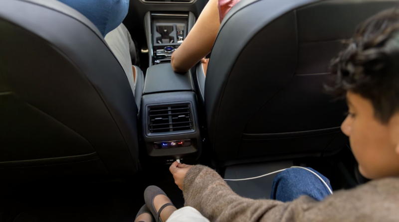 Niño en asiento trasero de SUV Volkswagen conecta cable en entrada tipo C.