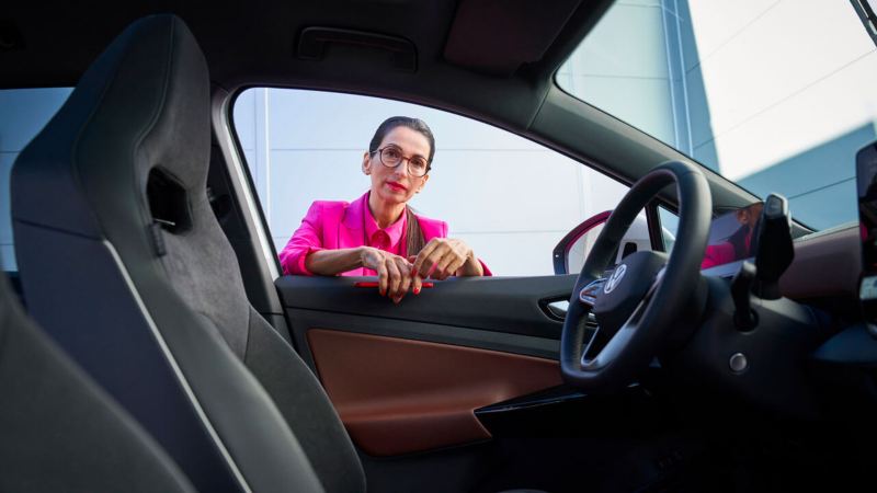 Vue sur une femme se tenant à la portière, depuis l'intérieur d'une voiture Volkswagen.