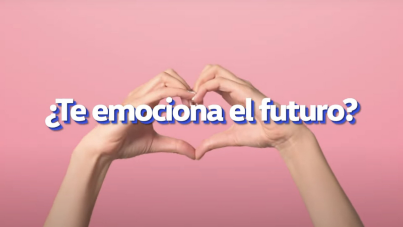 Manos forman un corazón frente a ciclorama de color rosa.