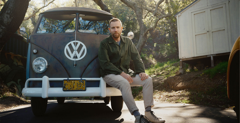 Volkswagen Brand Ambassador Ewan McGregor is sitting on the bumper of his VW Bulli.