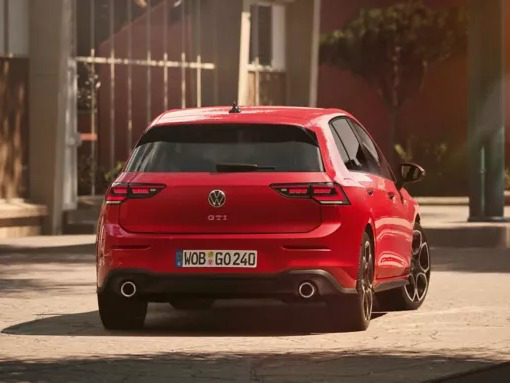 Rear view of a red Volkswagen Golf GTI parked outdoors, showcasing its dual exhaust tips and modern LED taillights.