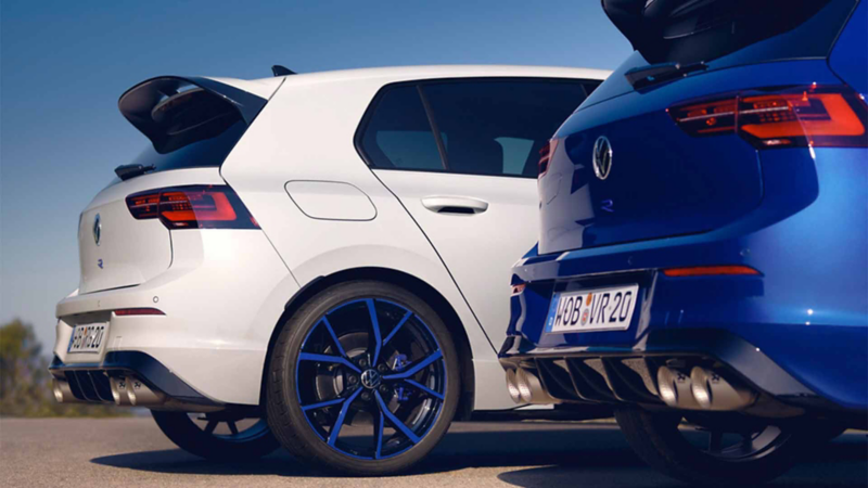 Dos autos deportivos Golf R 20 años en color blanco y azul estacionados en un espacio al aire libre.