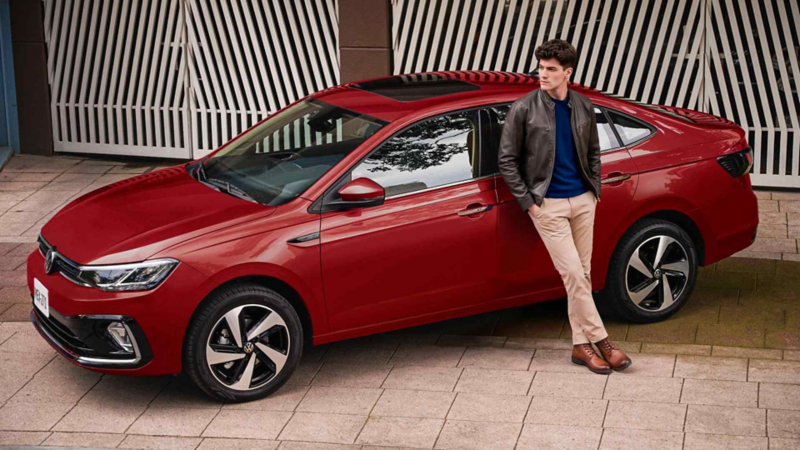 Hombre posa junto a un Volkswagen Virtus rojo con techo corredizo.Modificado con inteligencia artificial