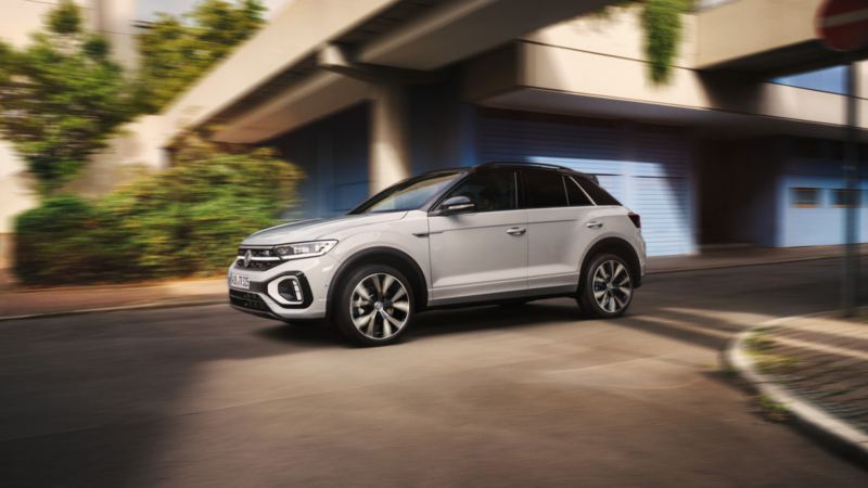 A sideview of a white 2022 T-Roc driving through a city