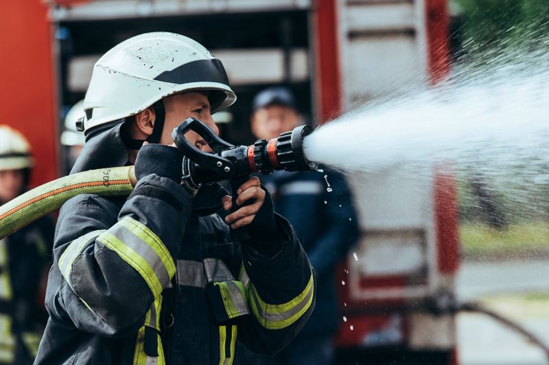 Feuerwehrmann mit Wasserschlauch in der Hand