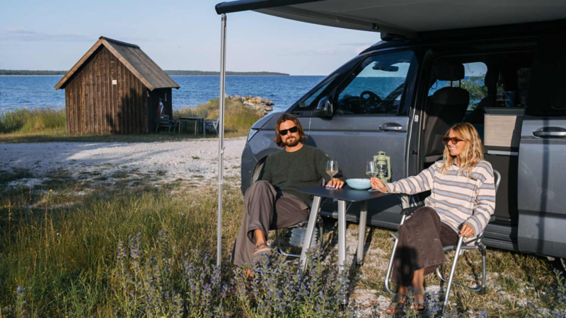 Caroline och Sebastian fikar under markisen på VW California på Gotland.