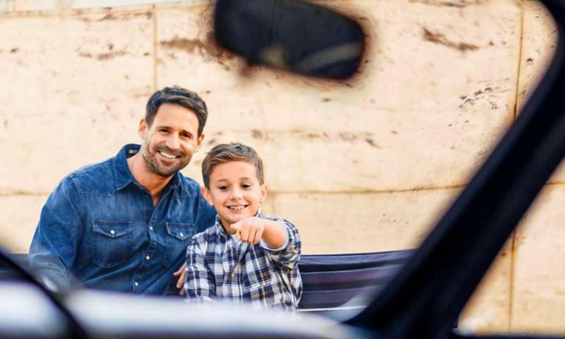 un père et son fils qui point du doigt un véhicule Volkswagen