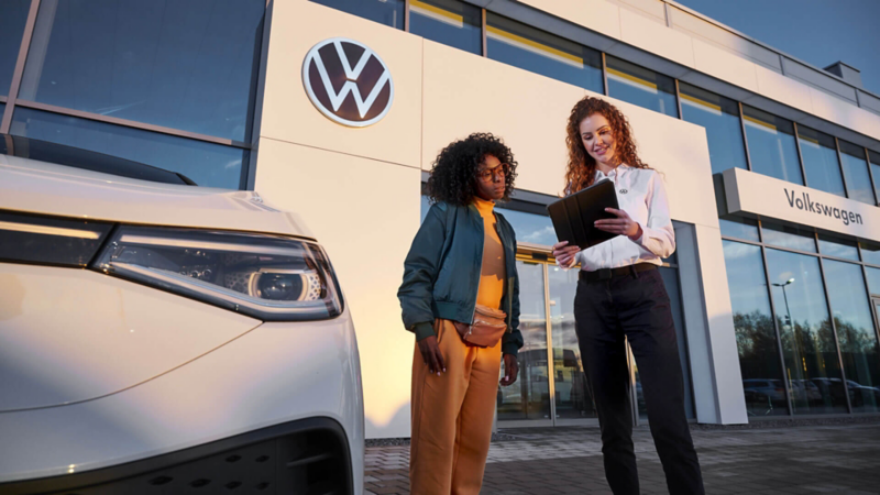 Une femme et une conseillère Volkswagen discutent devant une concession.