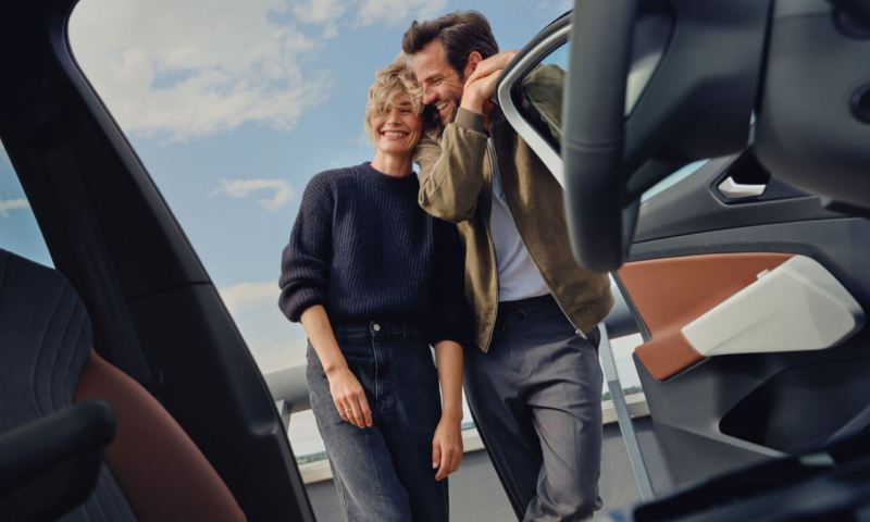 Una pareja sonriendo mirando el interior de un Volkswagen