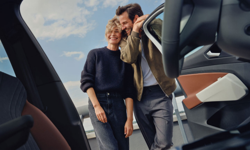 Una pareja sonriendo mirando el interior de un Volkswagen