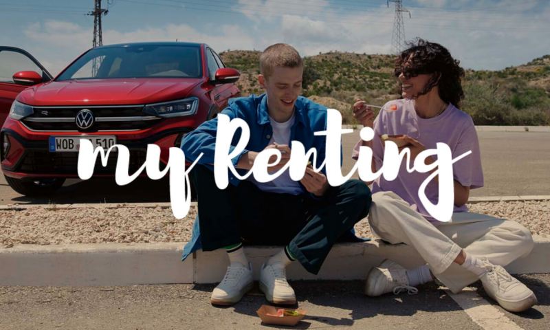 Una pareja sentada en un bordillo junto a un Volkswagen y el logo de My Renting