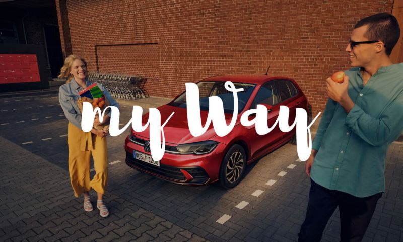 Una pareja saliendo de un supermercado junto a un Volkswagen y el logo de My Way