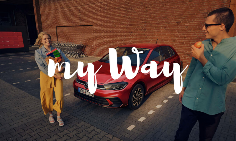 Una pareja saliendo de un supermercado junto a un Volkswagen y el logo de My Way