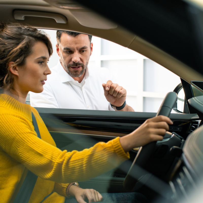 Woman in vehicle at Volkswagen dealership, link out to VW’s dealer search page