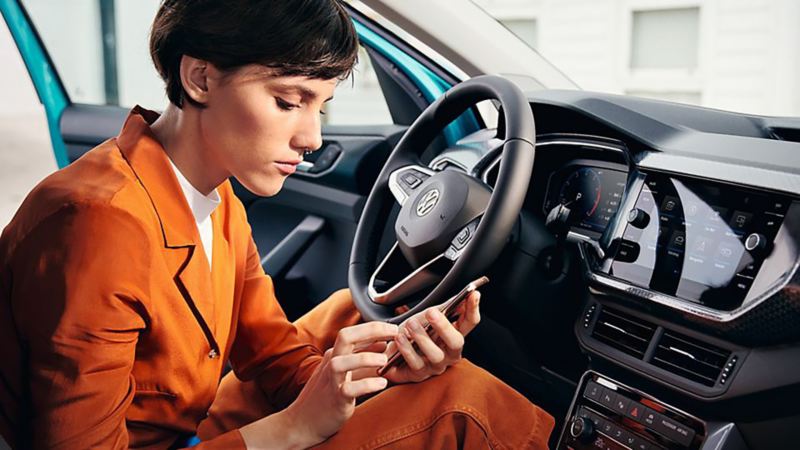 A lady using her smartphone in a T-Cross