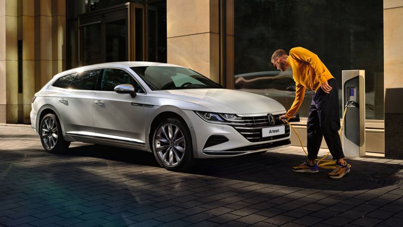 A man charging his Arteon Shooting Brake at the side of the road.