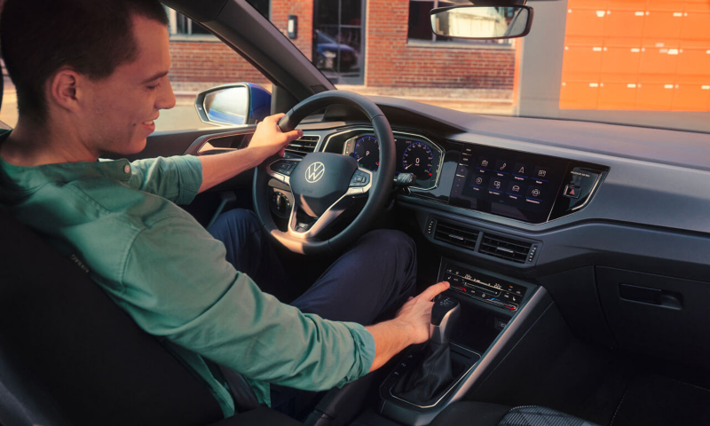 Un homme manipule les commandes de climatisation de sa Volkswagen Polo depuis le siège conducteur.