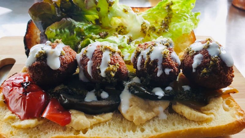 Streetfood-Gericht mit frittierten Bällchen und gegrilltem Gemüse.