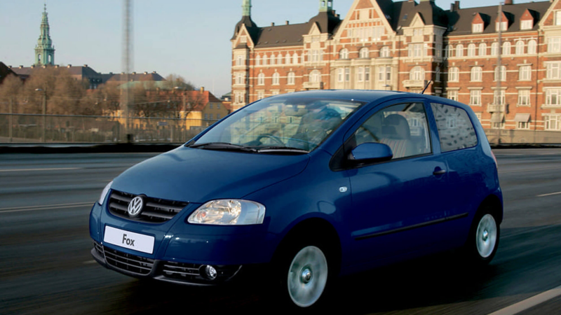 A blue Volkswagen Fox , driving across a bridge.