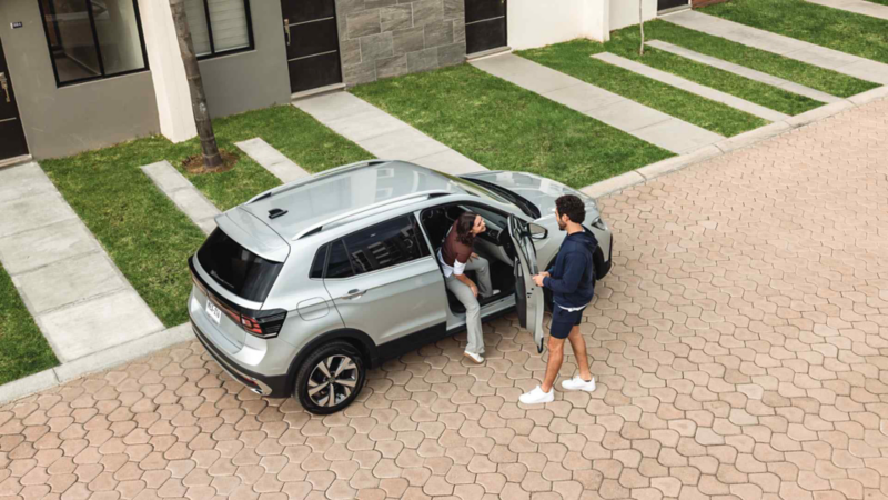 Pareja sube a Volkswagen Taigun 2025 gris con freno de estacionamiento electrónico.