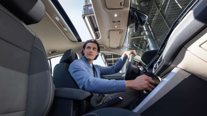 Conductor de un Volkswagen sujeta la palanca de velocidades mientras mira al exterior.