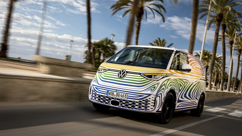 Van eléctrica de Volkswagen en una carretera con palmeras a su alrededor. 