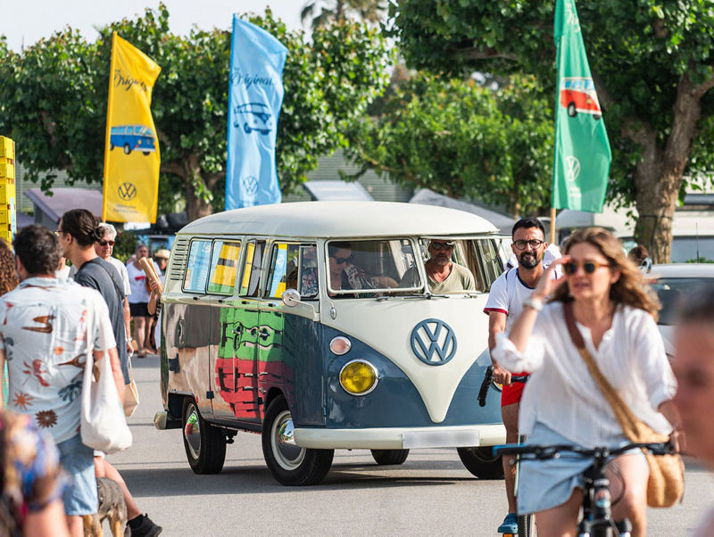 Una furgoneta Volkswagen clásica verde y blanca en la convención del año pasado, en primeros planos personas en bicicleta