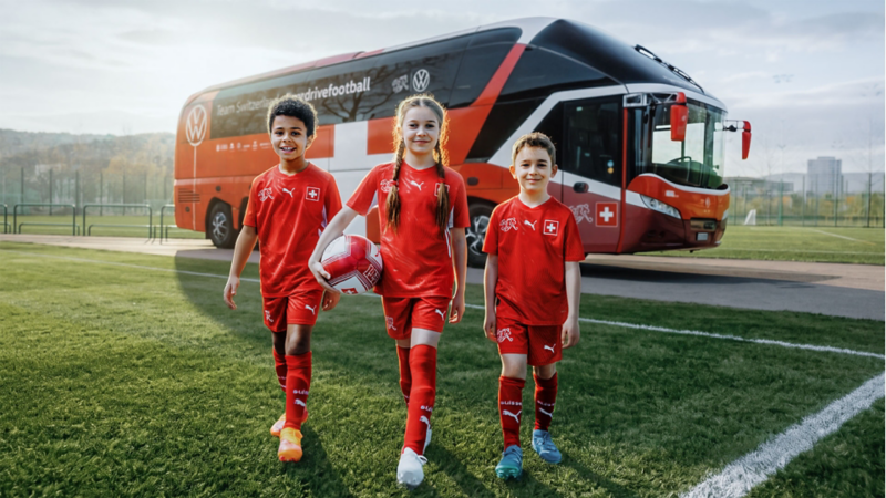 Drei Kinder stehen vor dem Bus der Schweizer Fussballnationalmannschaft.
