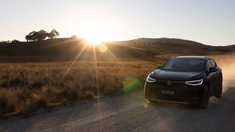 black ID.4 Pro driving on a rural road towards the viewer with a sunset in the background 