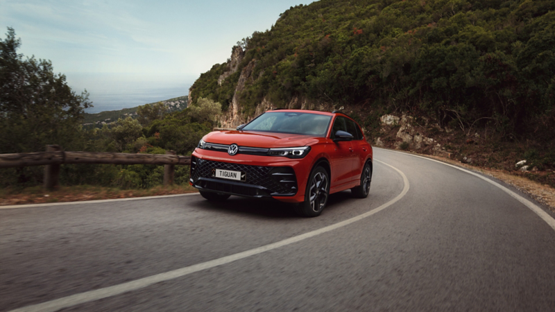 Red Tiguan driving along scenic landscape