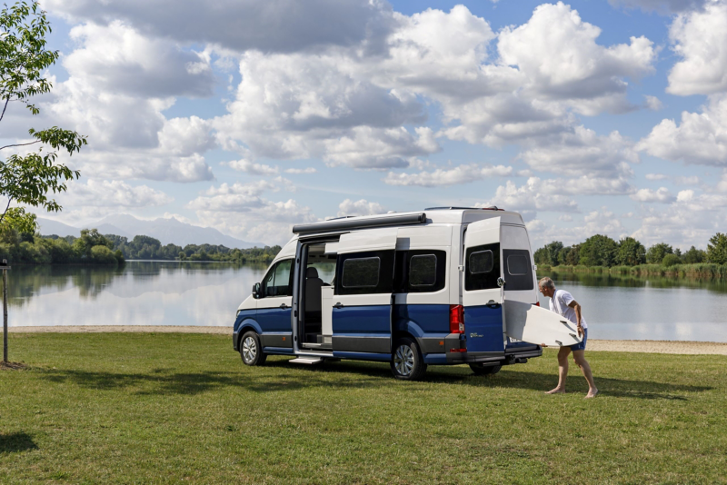 Mężczyzna pakujący deskę surfingową do Volkswagena Grand California