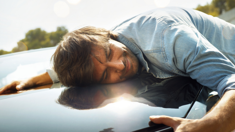 Man laying on the hood of a Volkswagen car