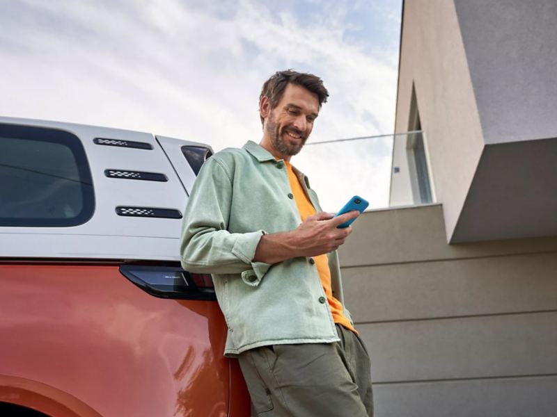 Man leaning against electric vehicle with mobile phone.