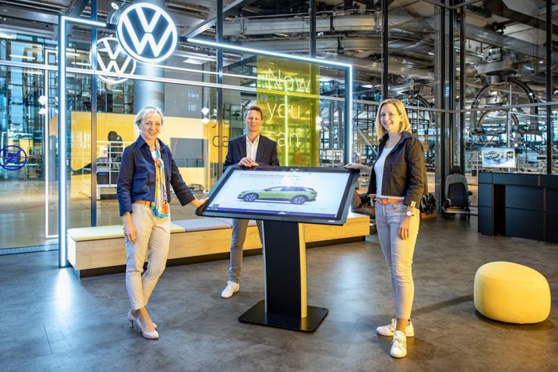 Drei Mitarbeiter stehen in der Gläsernen Manufaktur in Dresden von VW.