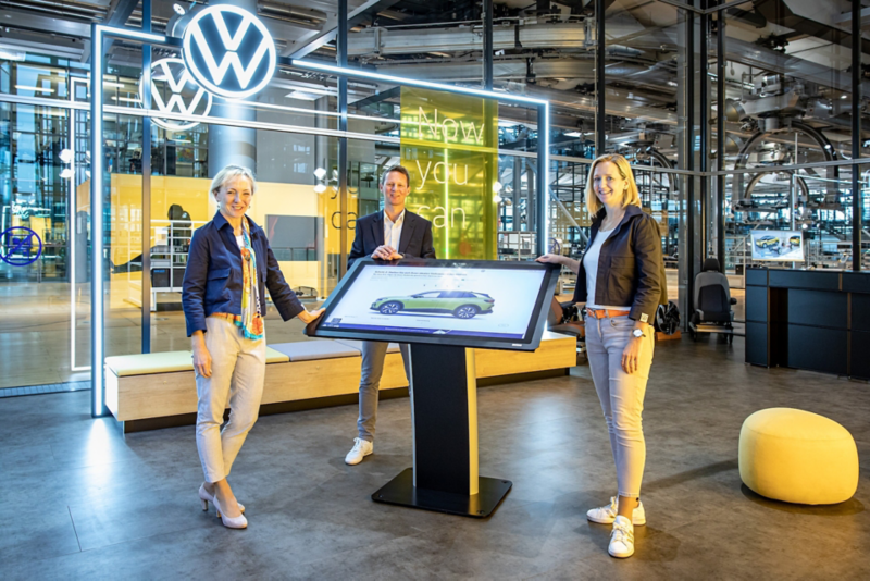 Drei Mitarbeiter stehen in der Gläsernen Manufaktur in Dresden von VW.