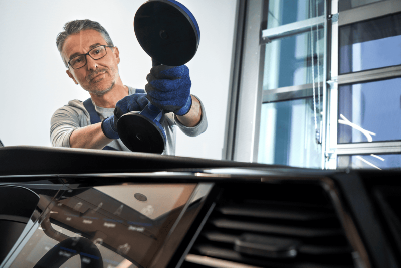 Mechanik wymienia przednią szybę w samochodzie marki Volkswagen.