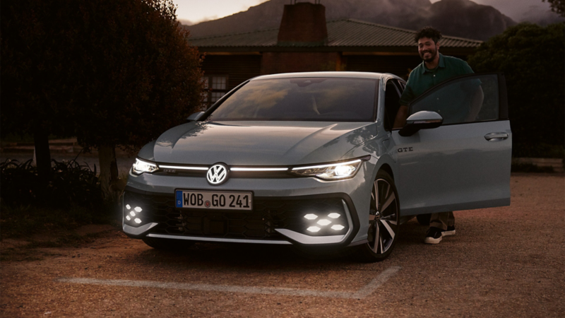 Mann steigt in einen grauen VW Golf GTE. 