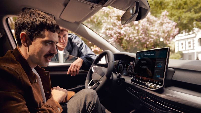 Zwei Männer schauen auf das Display eines VW.