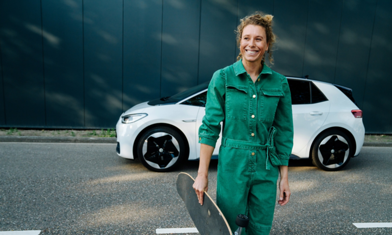 Frau mit Skateboard vor einem weißen VW ID.3 Modell.