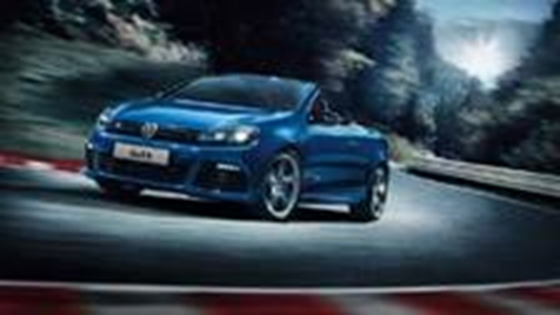 Schuin vooraanzicht van een oude blauwe Volkswagen Golf Cabriolet die door een bocht rijdt