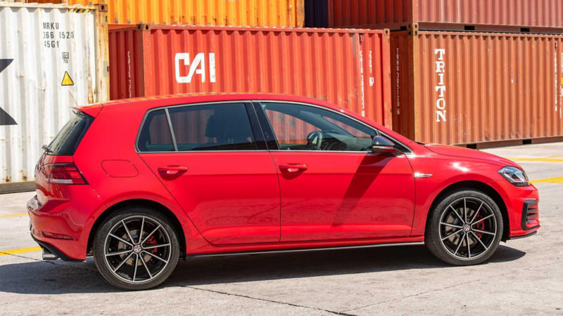 Golf GTI en color rojo delante de unos contenedores.